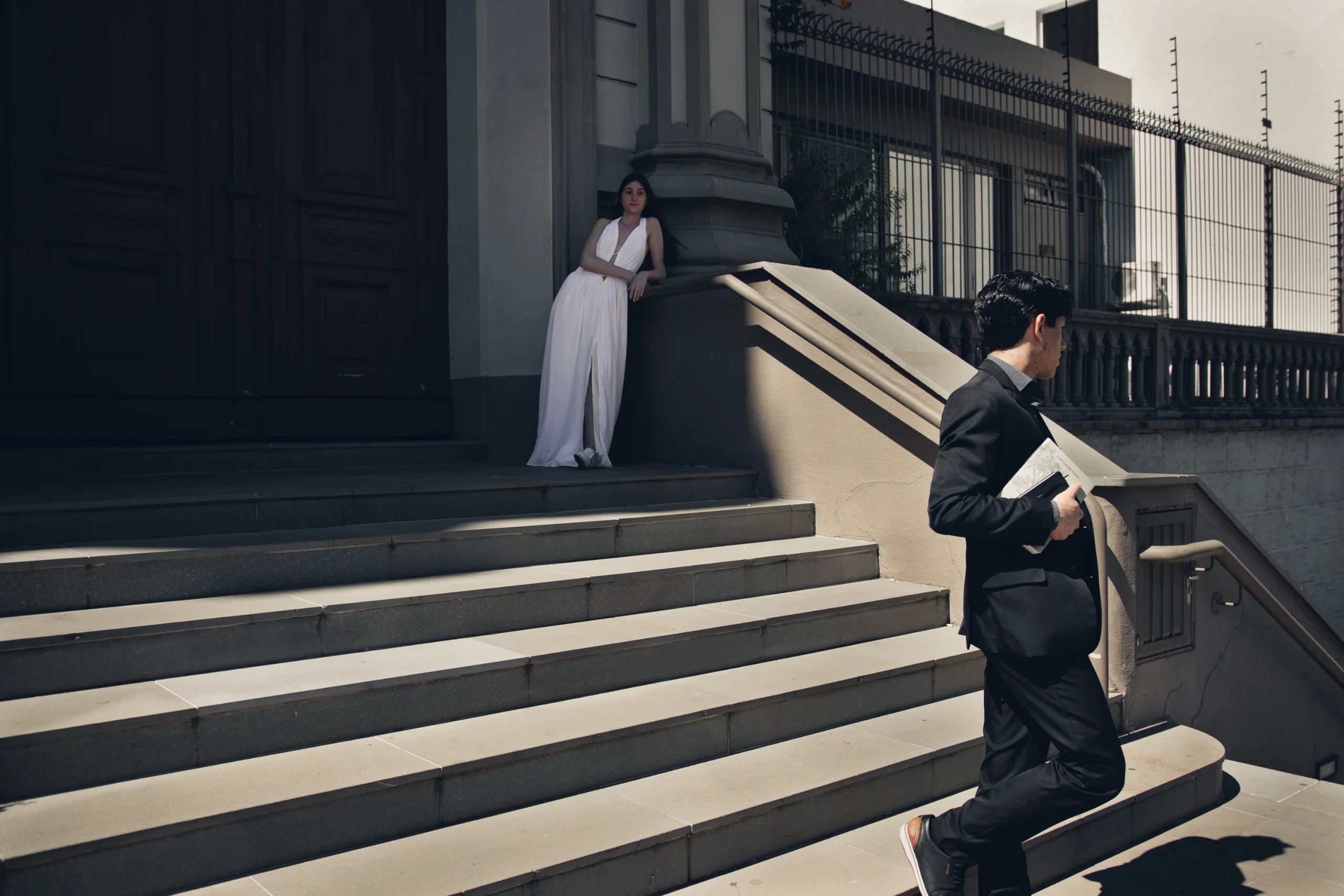 O autor, retirando-se pelas escadas externas à Catedral, e Mariana observando, ao fundo.